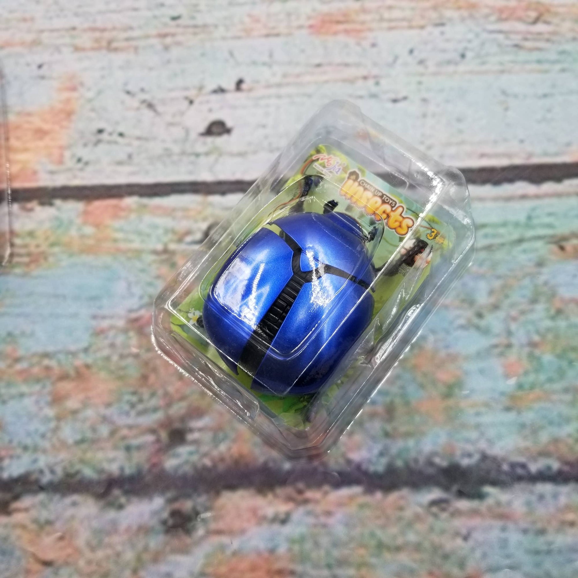 Blue toy car in clear packaging on a textured surface