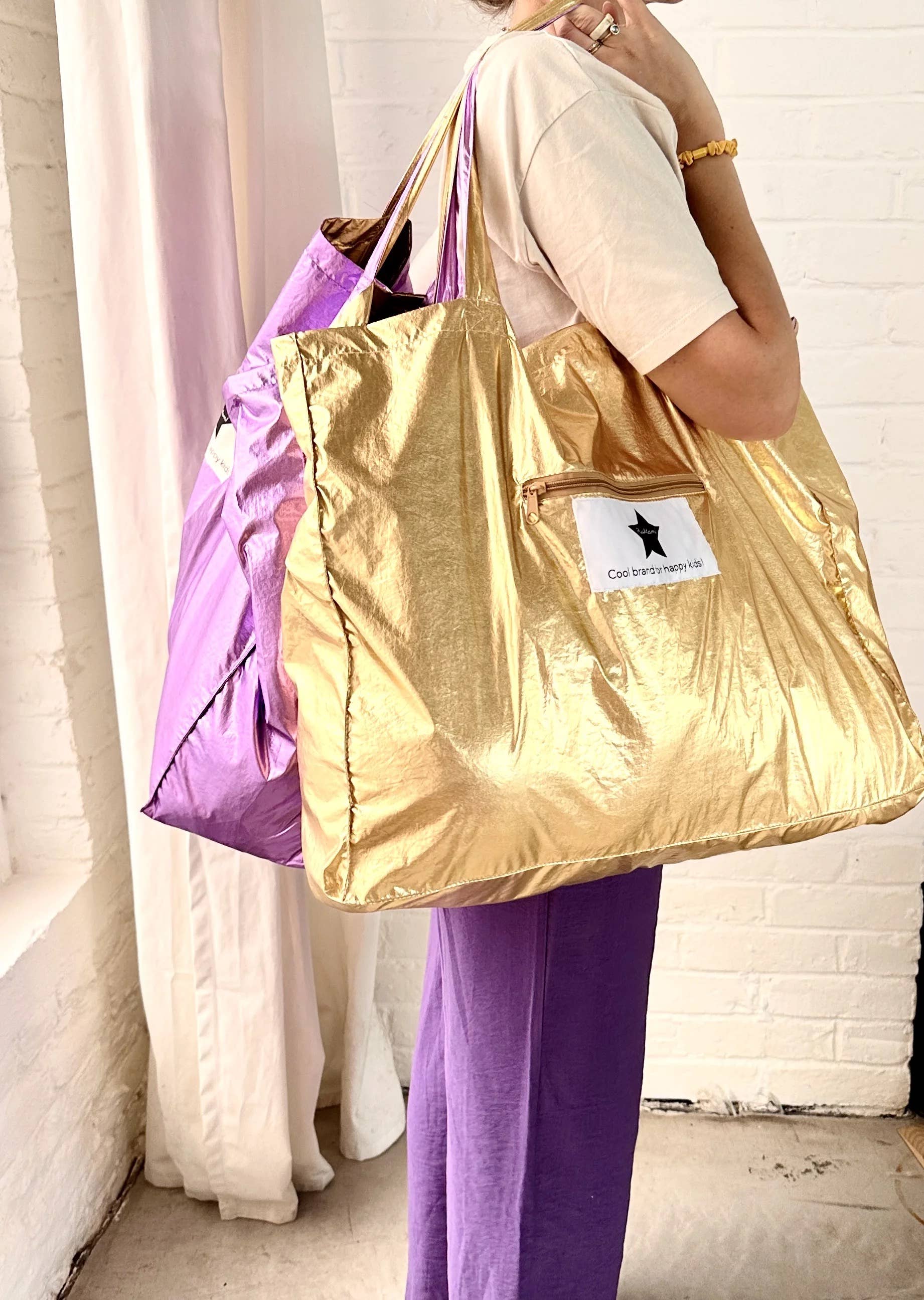 Person holding a gold and purple reusable bags with a visible brand logo.