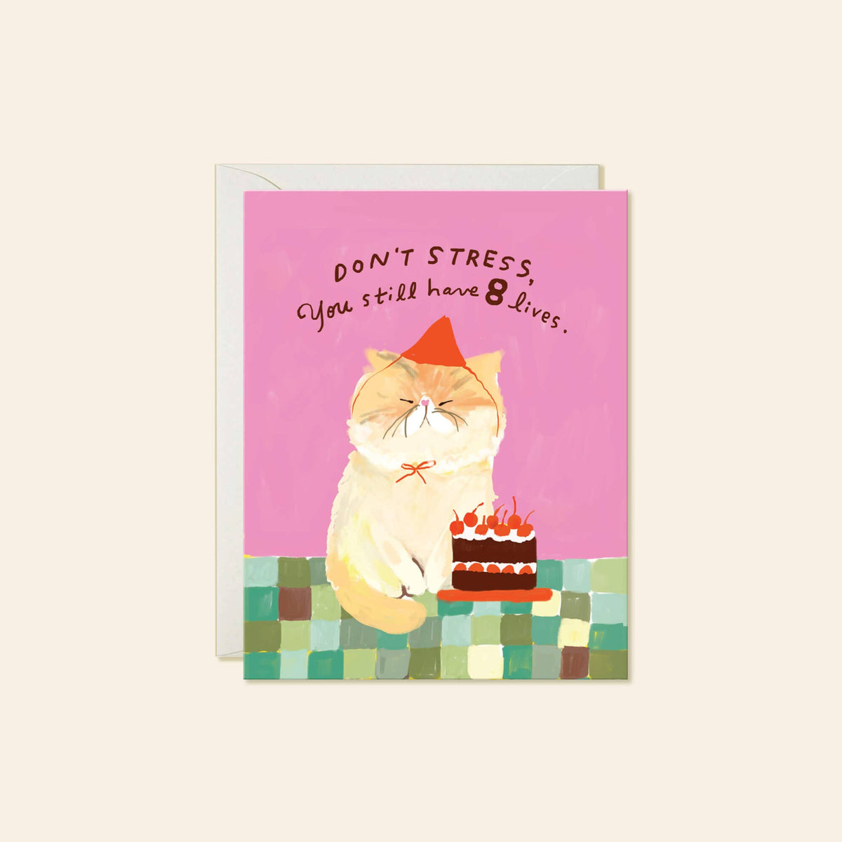 A greeting card featuring a cartoon orange cat wearing a party hat and sitting next to a small birthday cake, with the text 'DON'T STRESS, You still have 8 lives.' on a pink background.