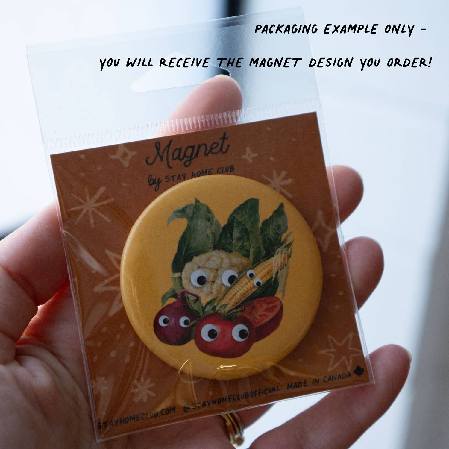Magnet packaging with cartoon vegetables on a yellow background, held by a hand.