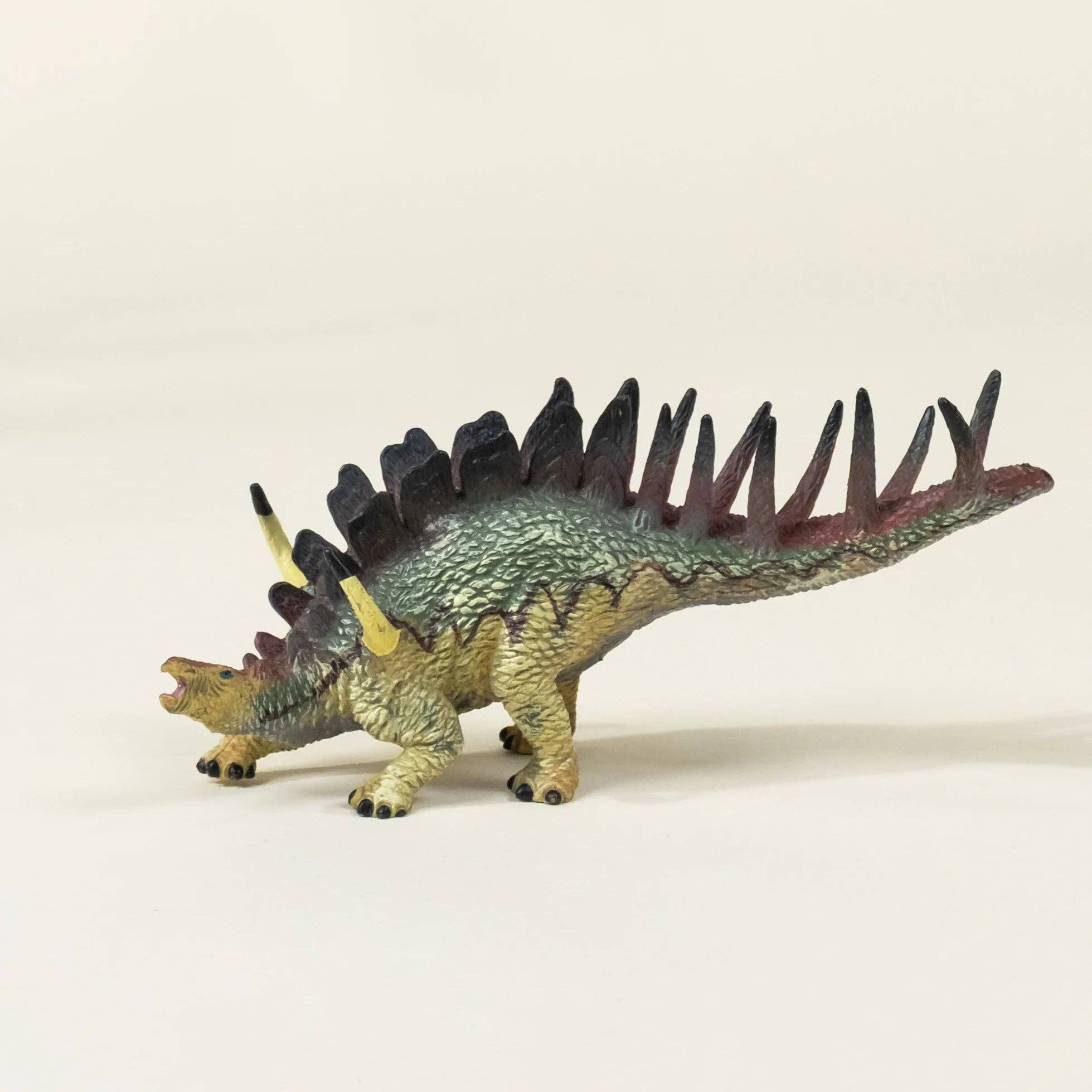 Toy Stegosaurus dinosaur figure on a beige background