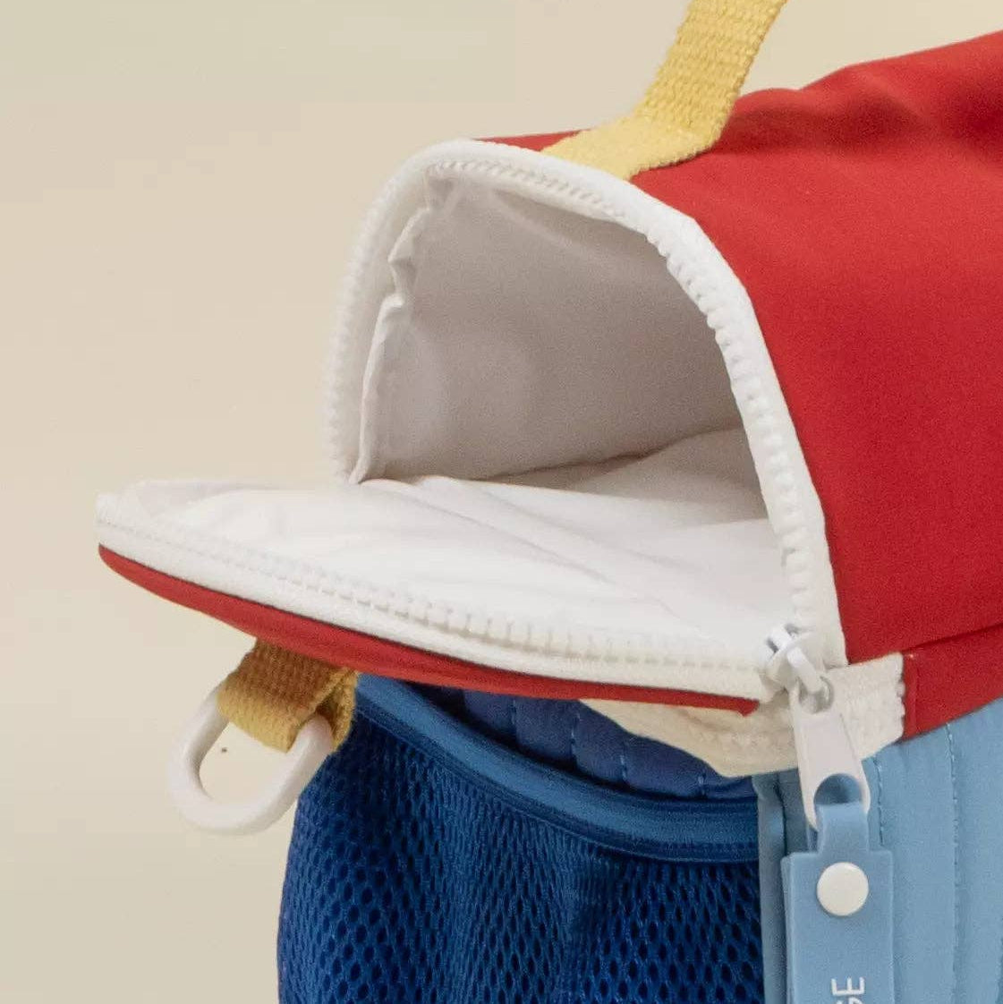 Red and blue bag with a visible brand logo on a beige background