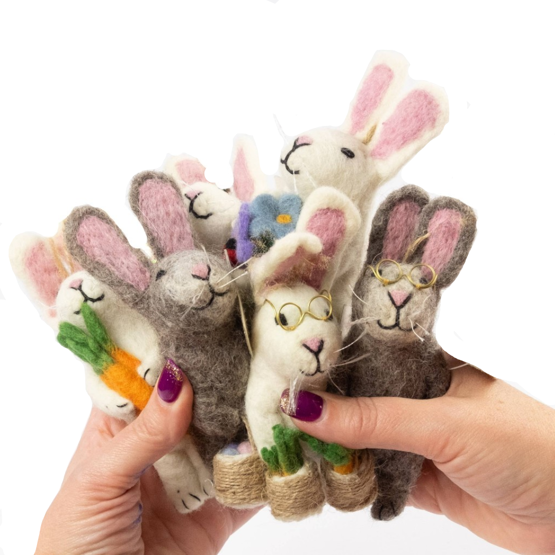 Hand holding six felt rabbit dolls with various accessories on a white background