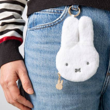 White fluffy bunny keychain attached to blue jeans