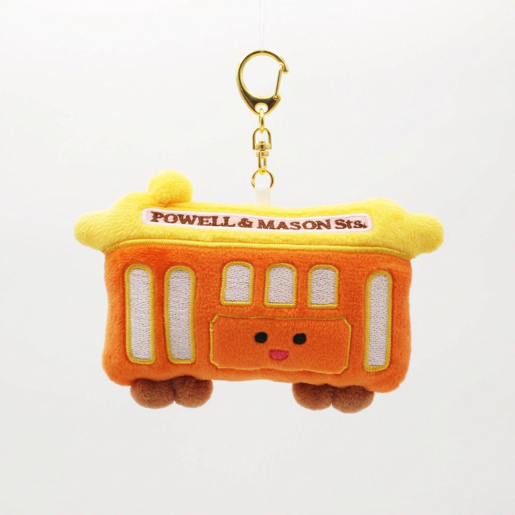 A San Francisco Powell & Mason Street Car plush keychain bag in orange and yellow, featuring embroidered details, a cute face, and a gold clasp with a black keyring on a white background.