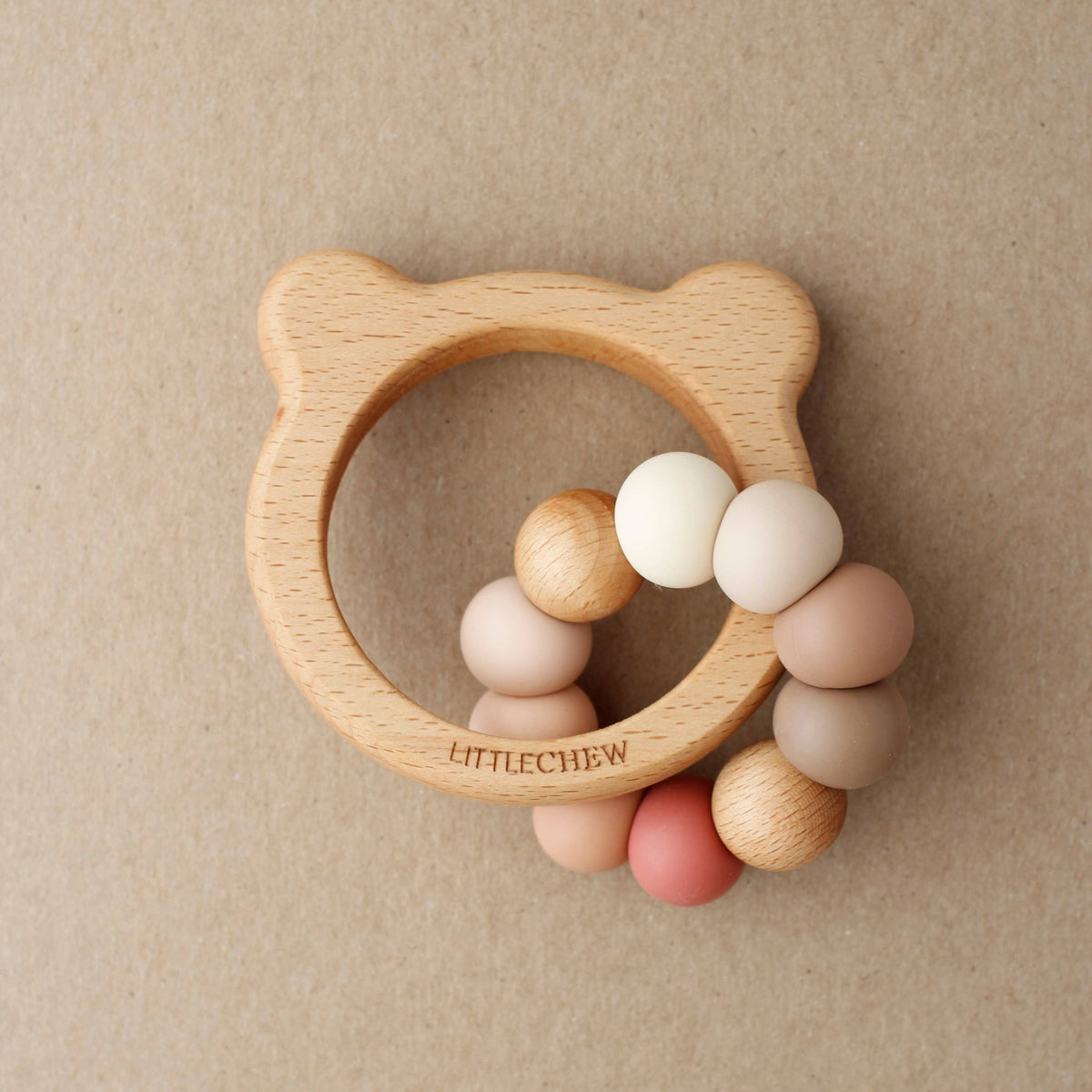 Wooden teething ring with colorful beads on a beige background