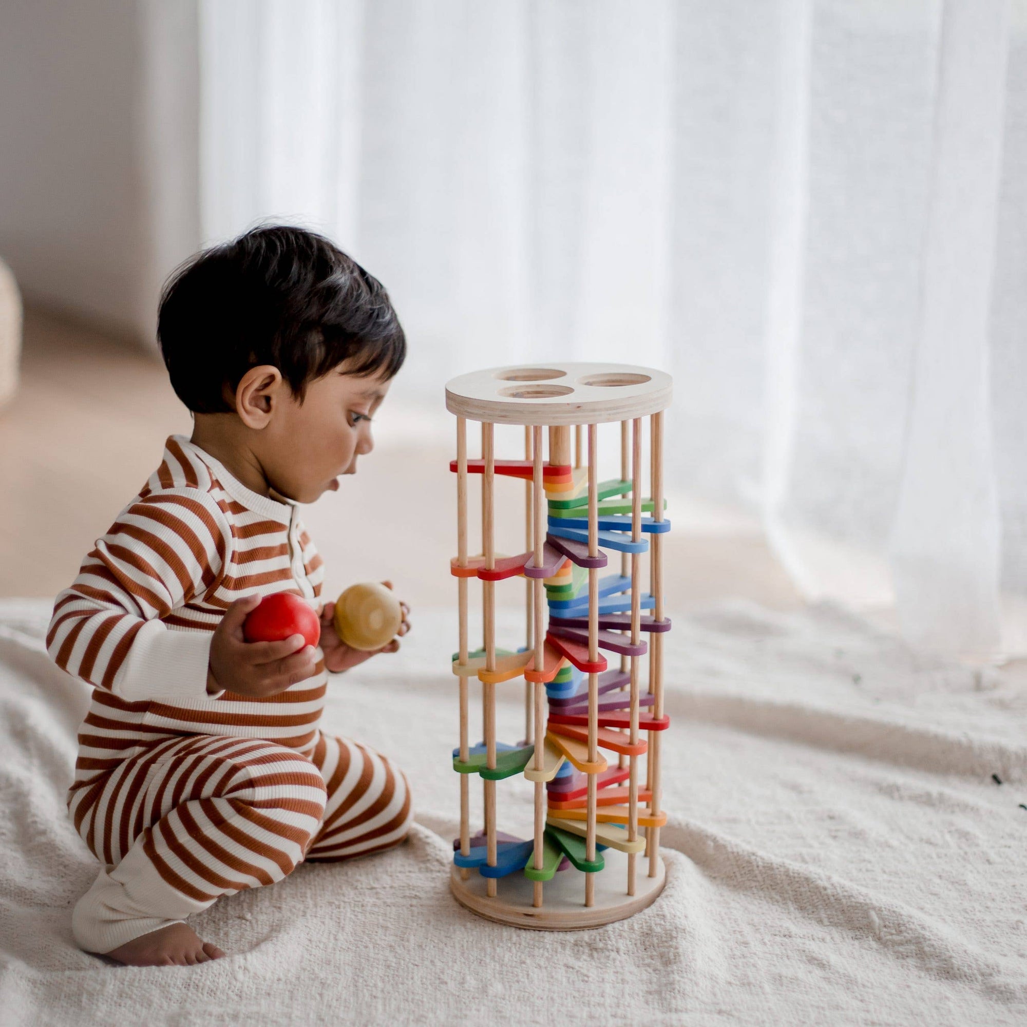 Child playing with a colorful wooden toy on a light surface.