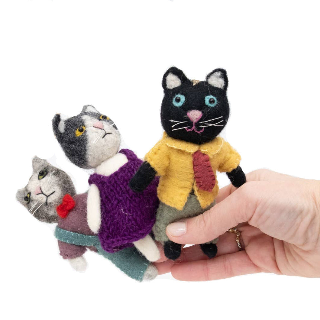 Hand holding three cat-shaped toys on a white background