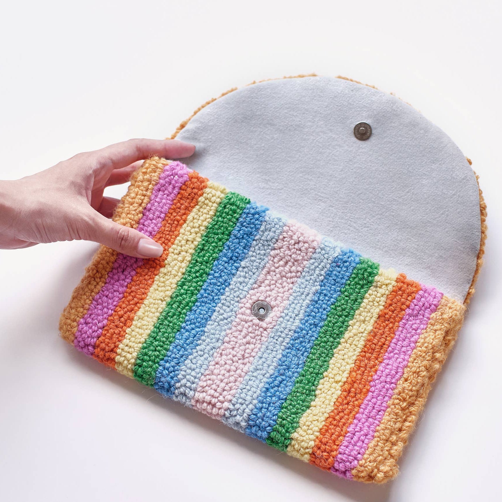Handmade pouch with rainbow pattern and gray top held by a hand on a white background