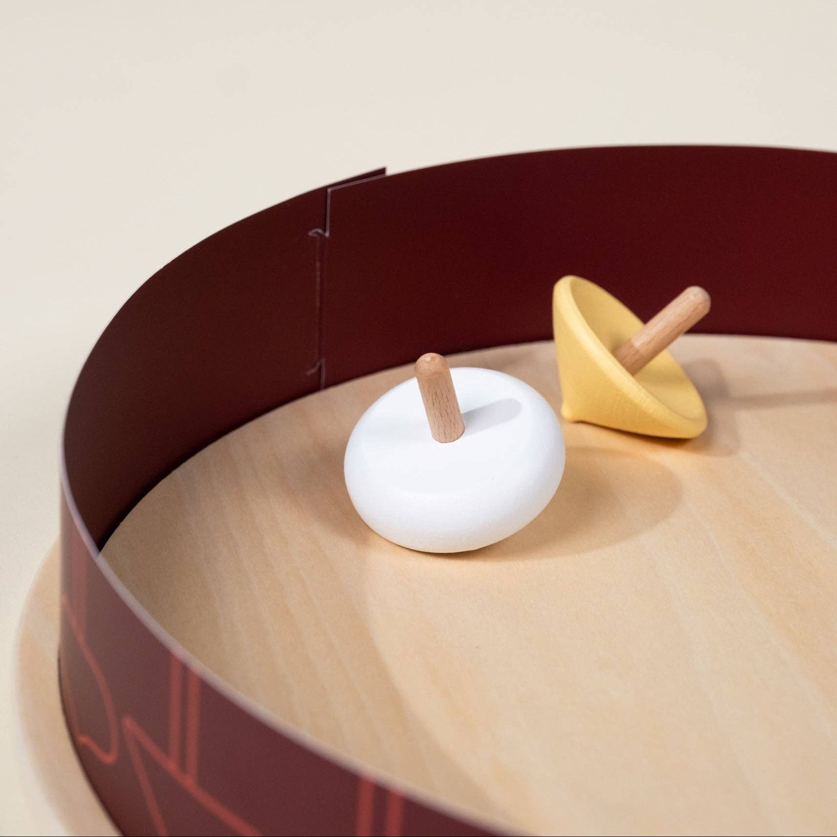 Two wooden toys on a circular tray with a beige background