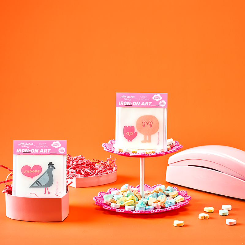 Pink vintage phone and small decorative items on an orange background