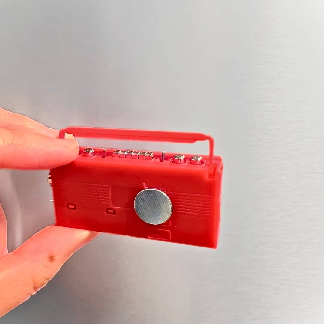 Red handheld electronic device held by a hand against a gray background