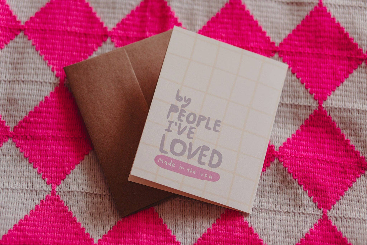Card with text 'By people I've loved' on a pink and gray checkered background