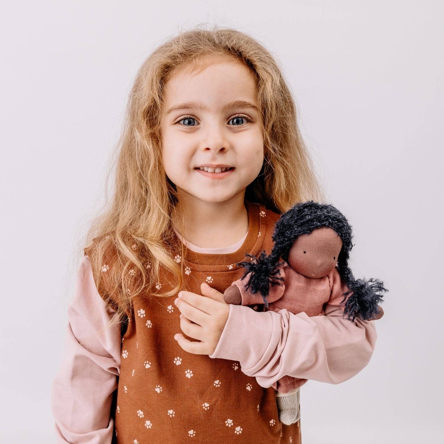 Young girl holding a doll with a neutral background