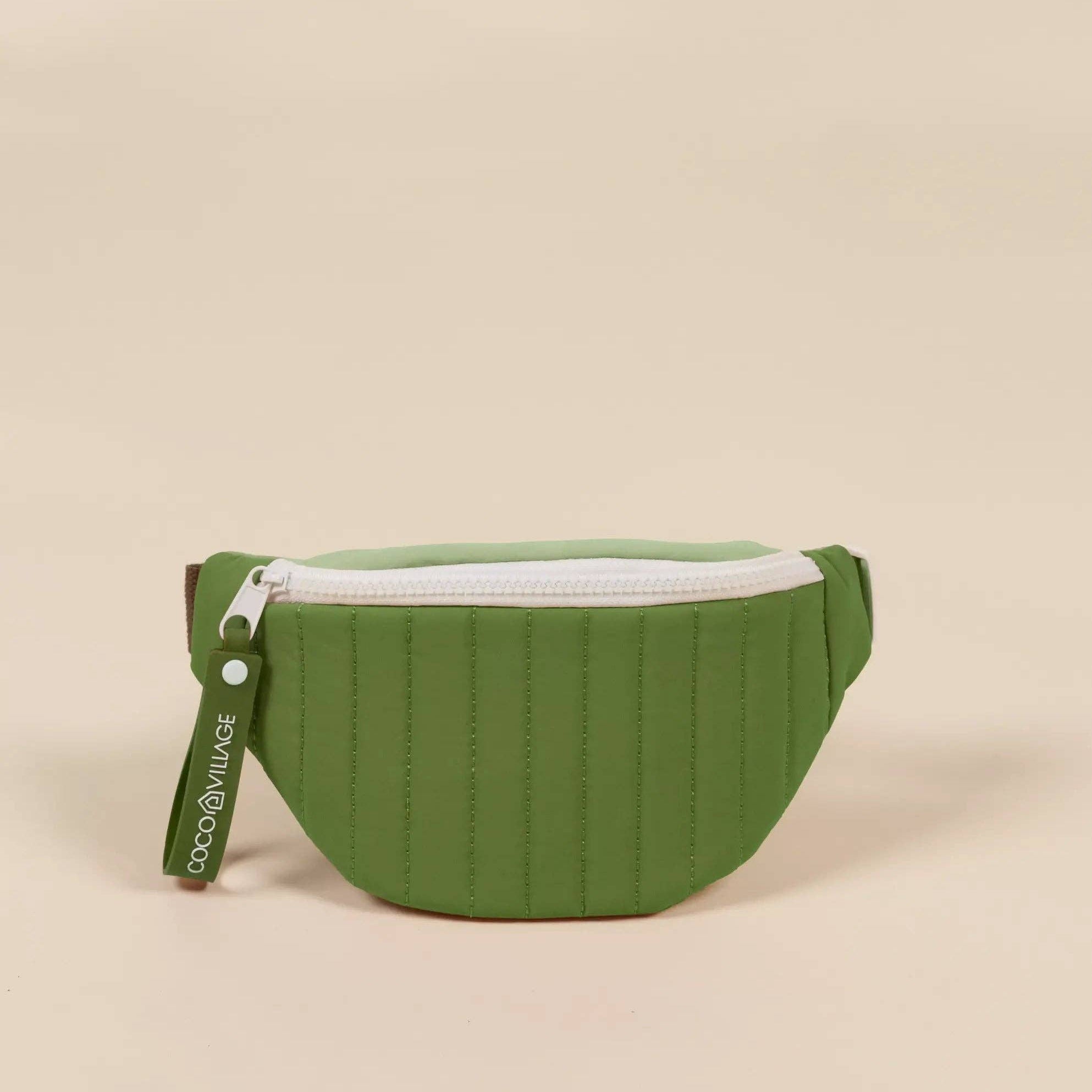 Green waist bag with a white zipper on a beige background