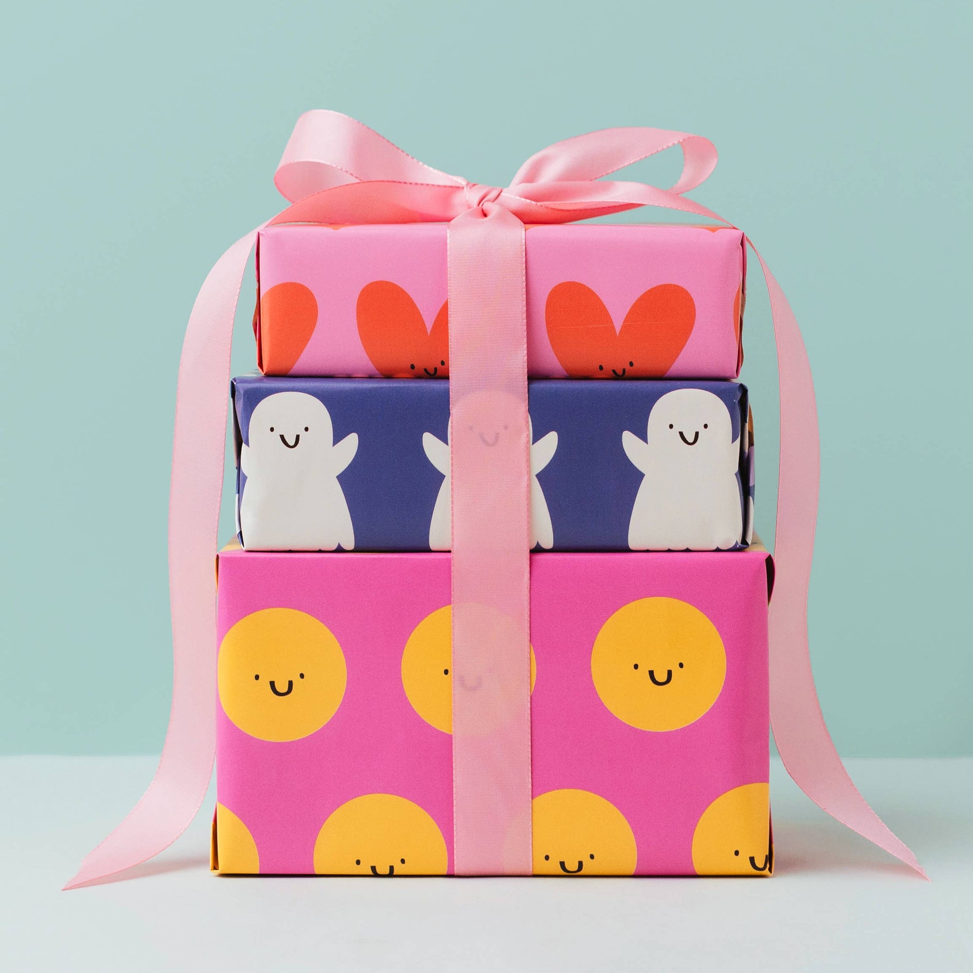 Stack of gift boxes with colorful wrapping paper and pink ribbon on a light blue background