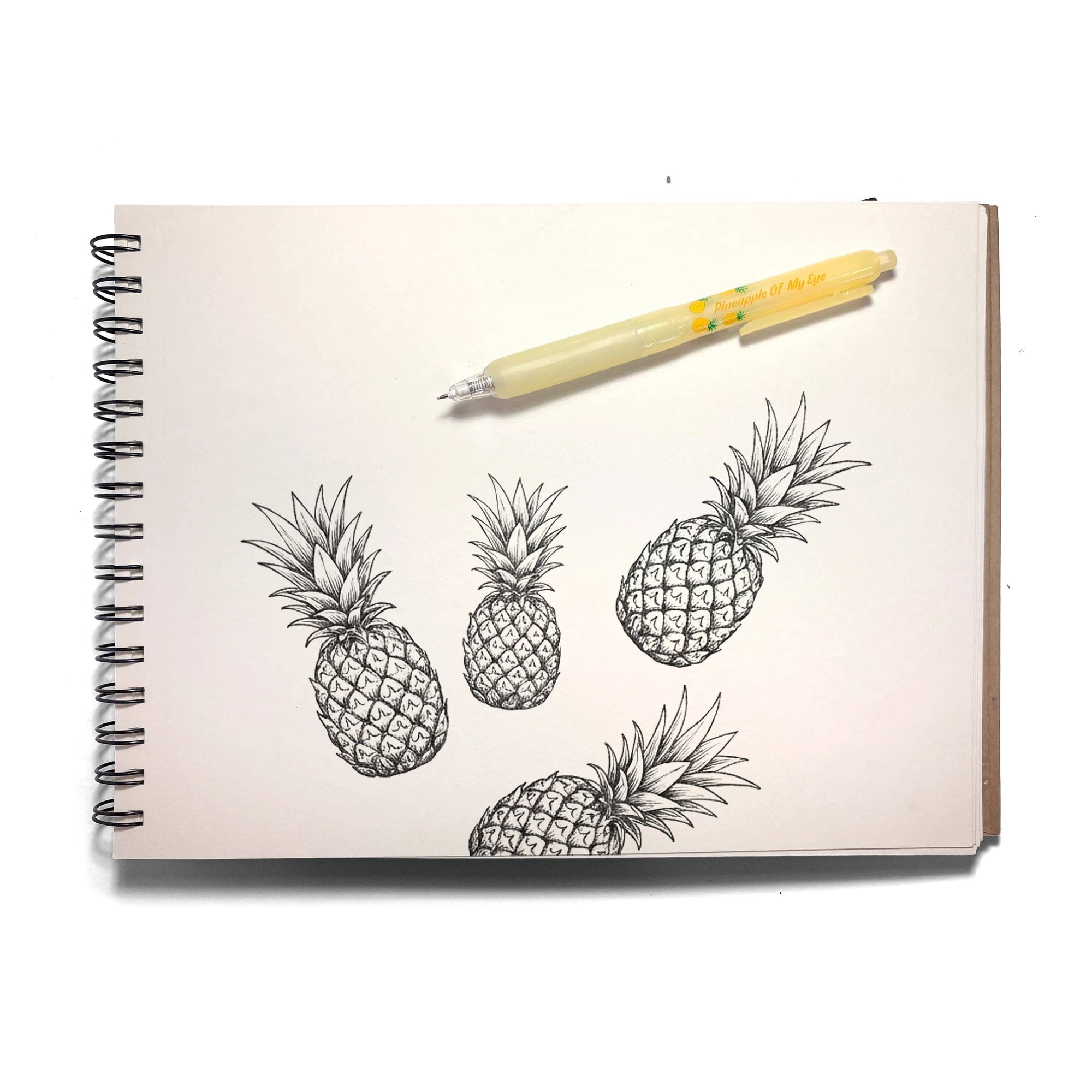 Notebook with pineapple illustrations and a pen on a white background