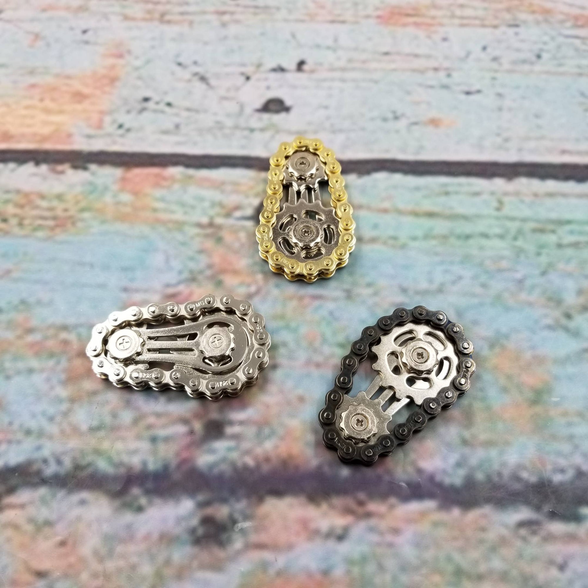 Three metallic chain accessories on a textured surface