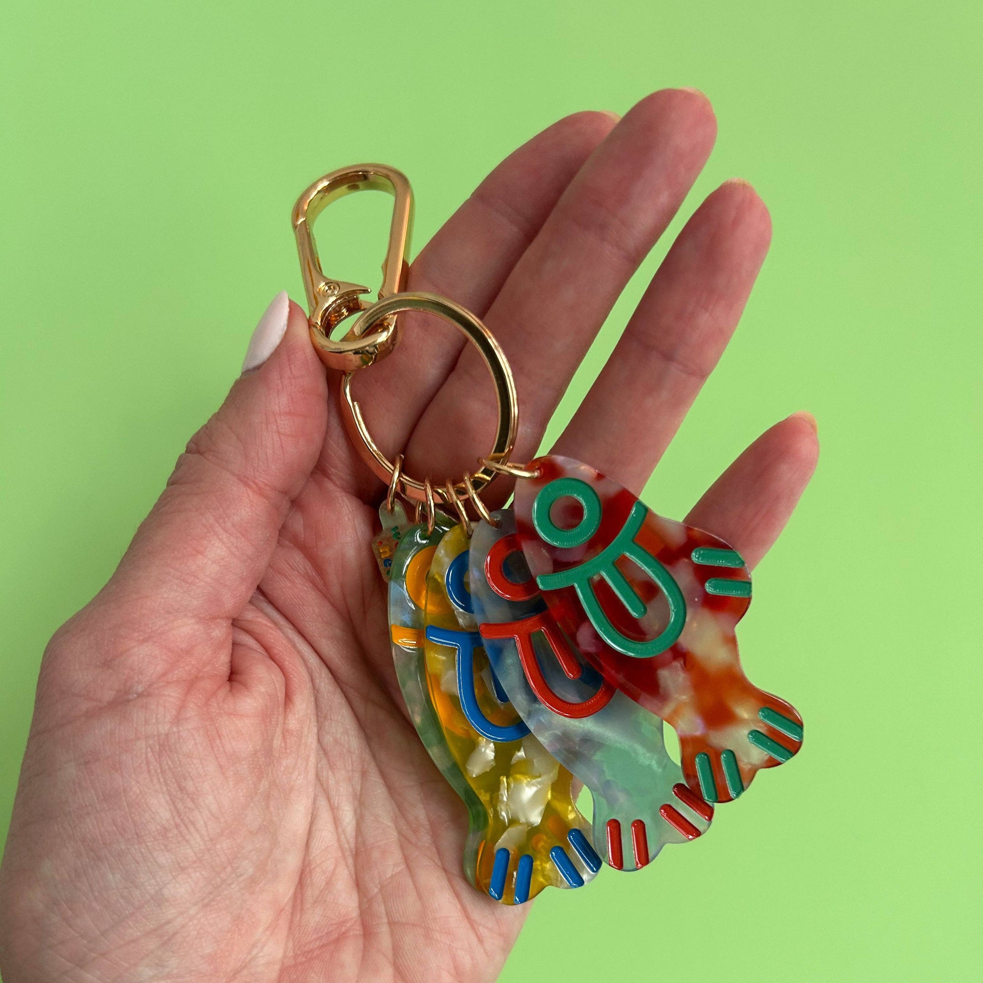 Hand holding a colorful keychain against a green background