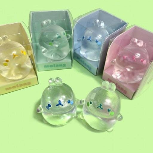 Clear figurines with colorful faces in packaging on a green background