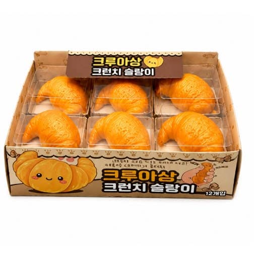 A box of 12 cute, pumpkin-shaped croissants in a brown cardboard display box with Korean text and cartoon illustrations.