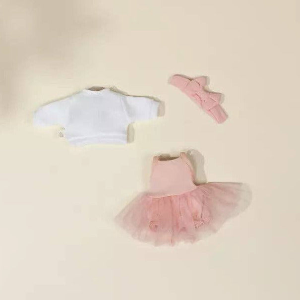 Children's outfit with a white top and pink tutu skirt on a beige background