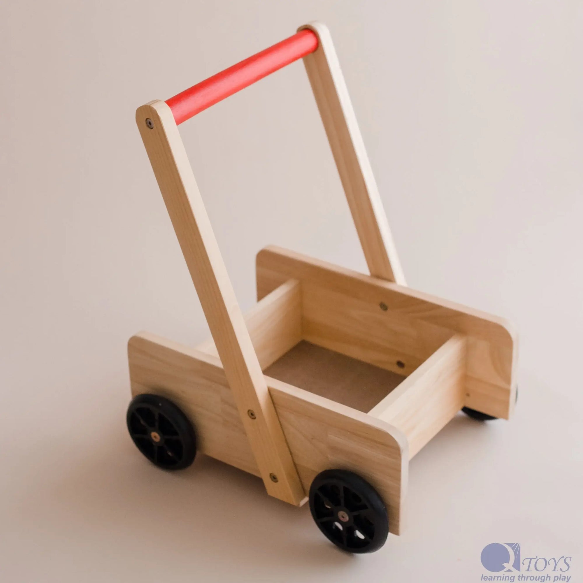 Wooden toy push cart with a red handle on a light background