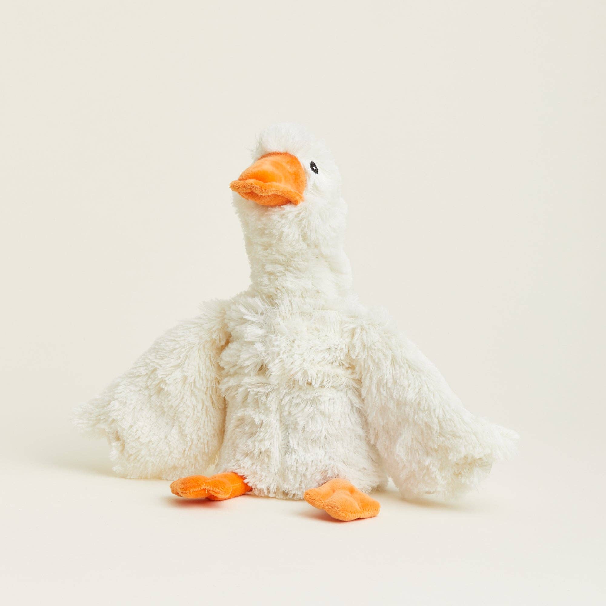 Plush toy goose with orange beak and feet on a light beige background