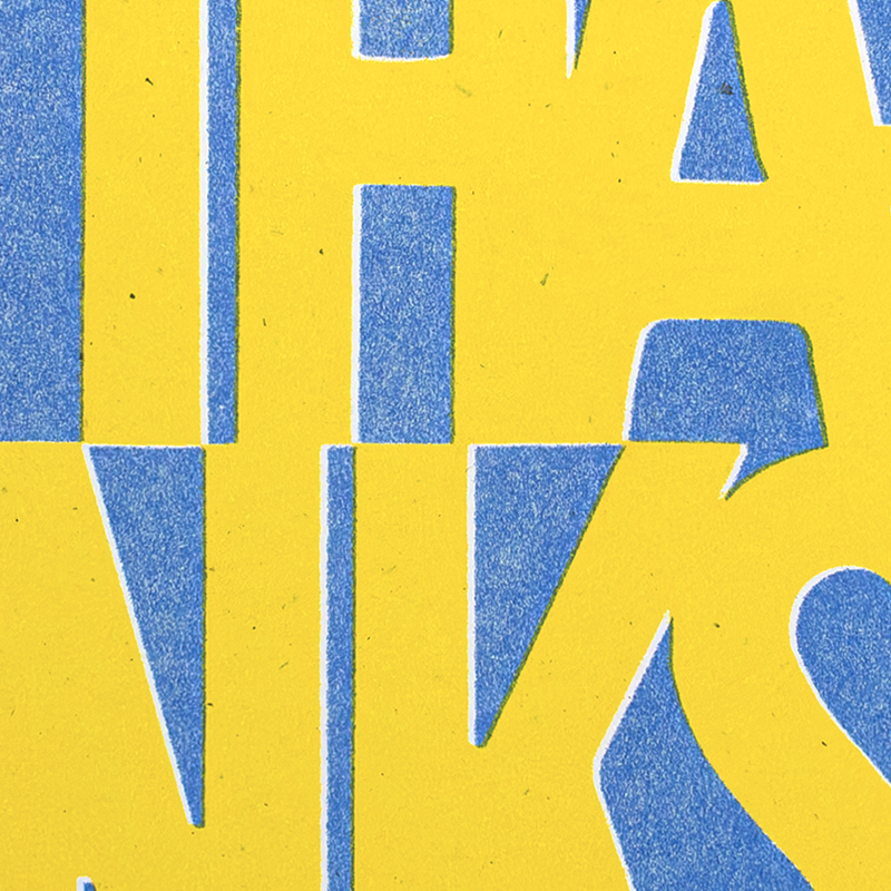 A close-up of a yellow and blue graphic design with bold geometric letterforms and textured paper-like appearance.