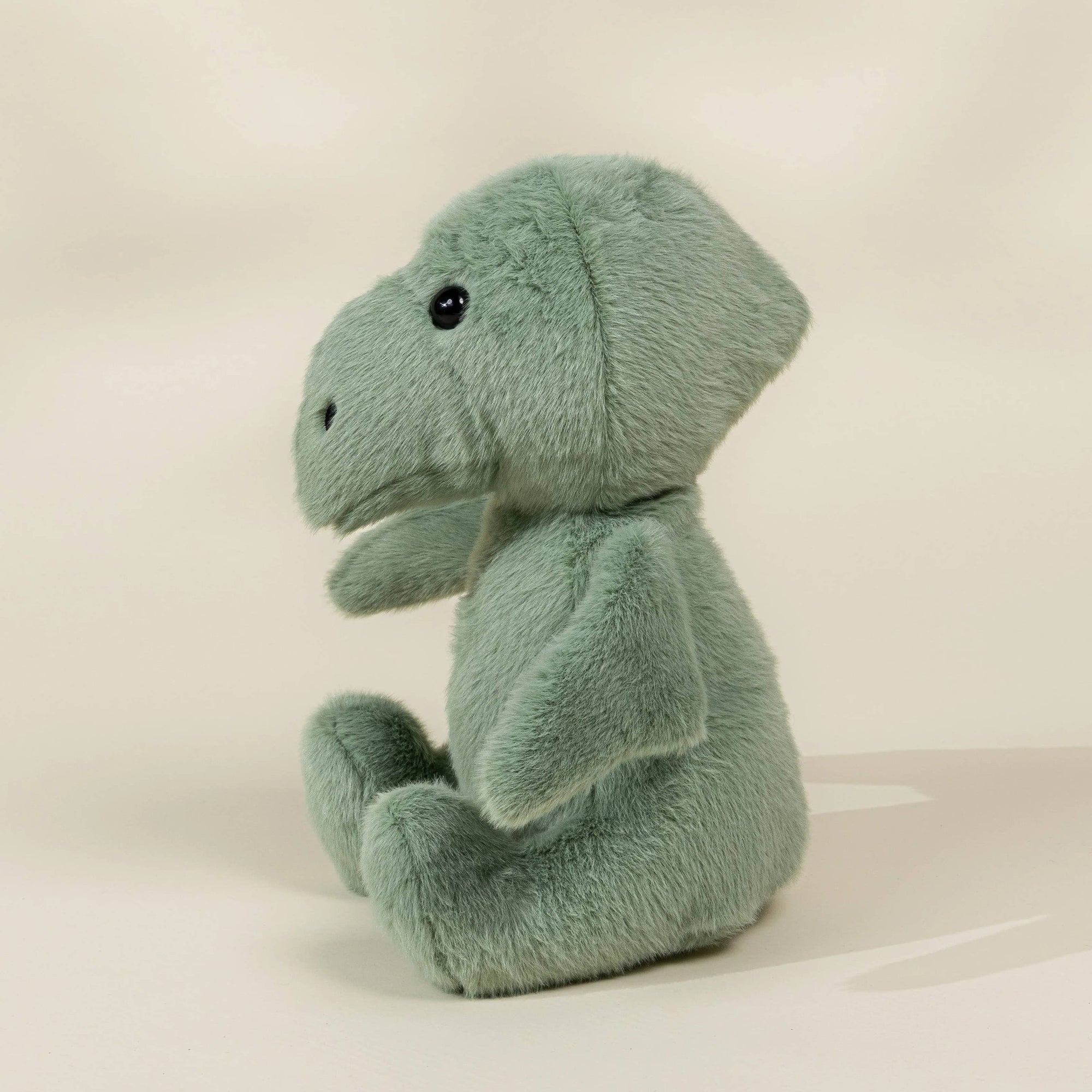 Plush toy resembling a dinosaur on a beige background