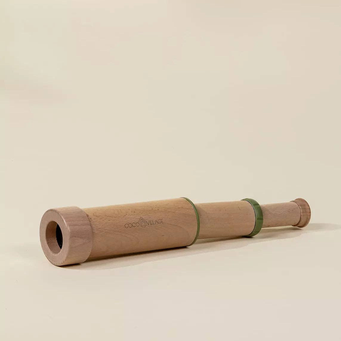 Wooden telescope with green band on a beige background
