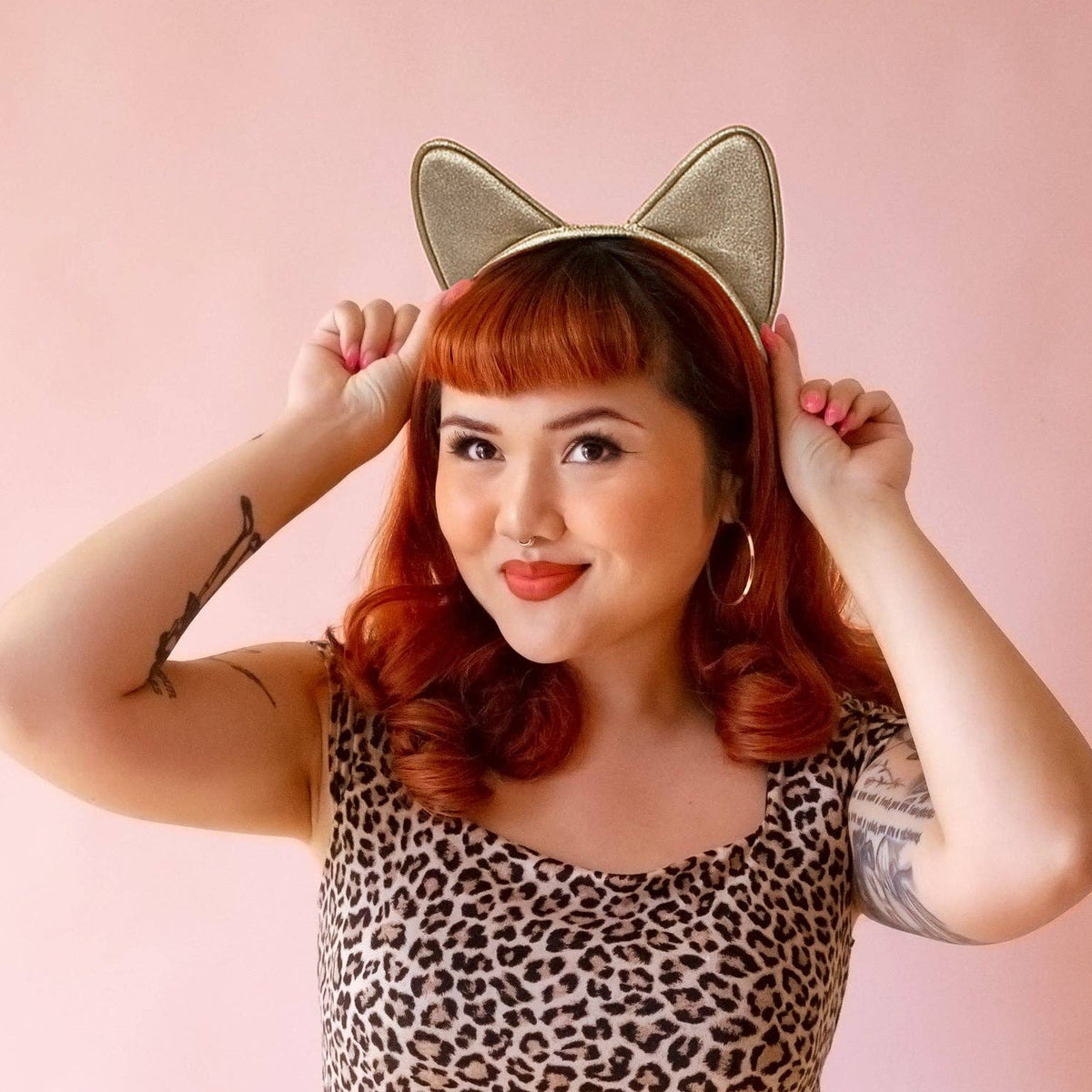 Woman wearing cat ears with a pink background
