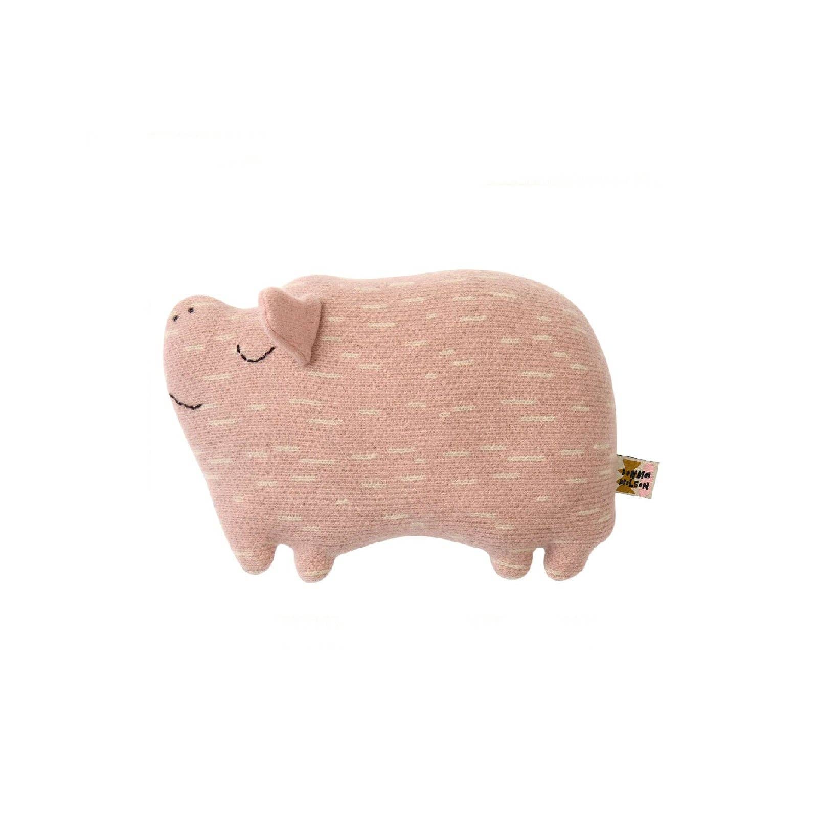 A pink knitted plush pig toy with embroidered closed eyes and a small tag attached to its tail, shown on a plain white background.