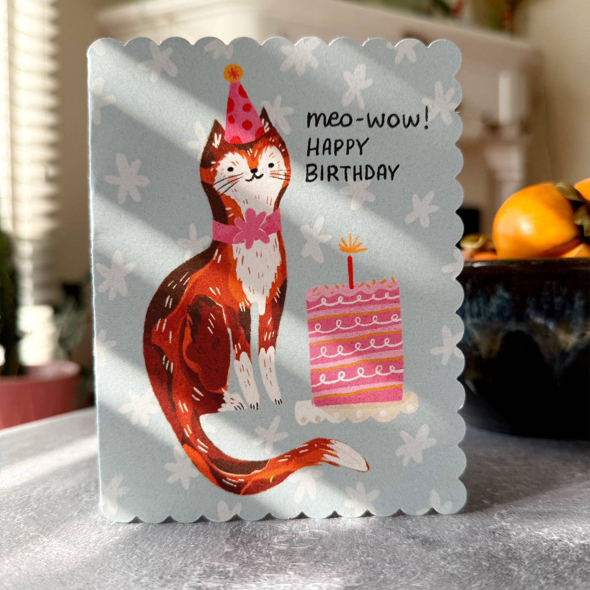 Birthday card with a cat illustration and 'meo-wow! Happy Birthday' text on a light blue background.