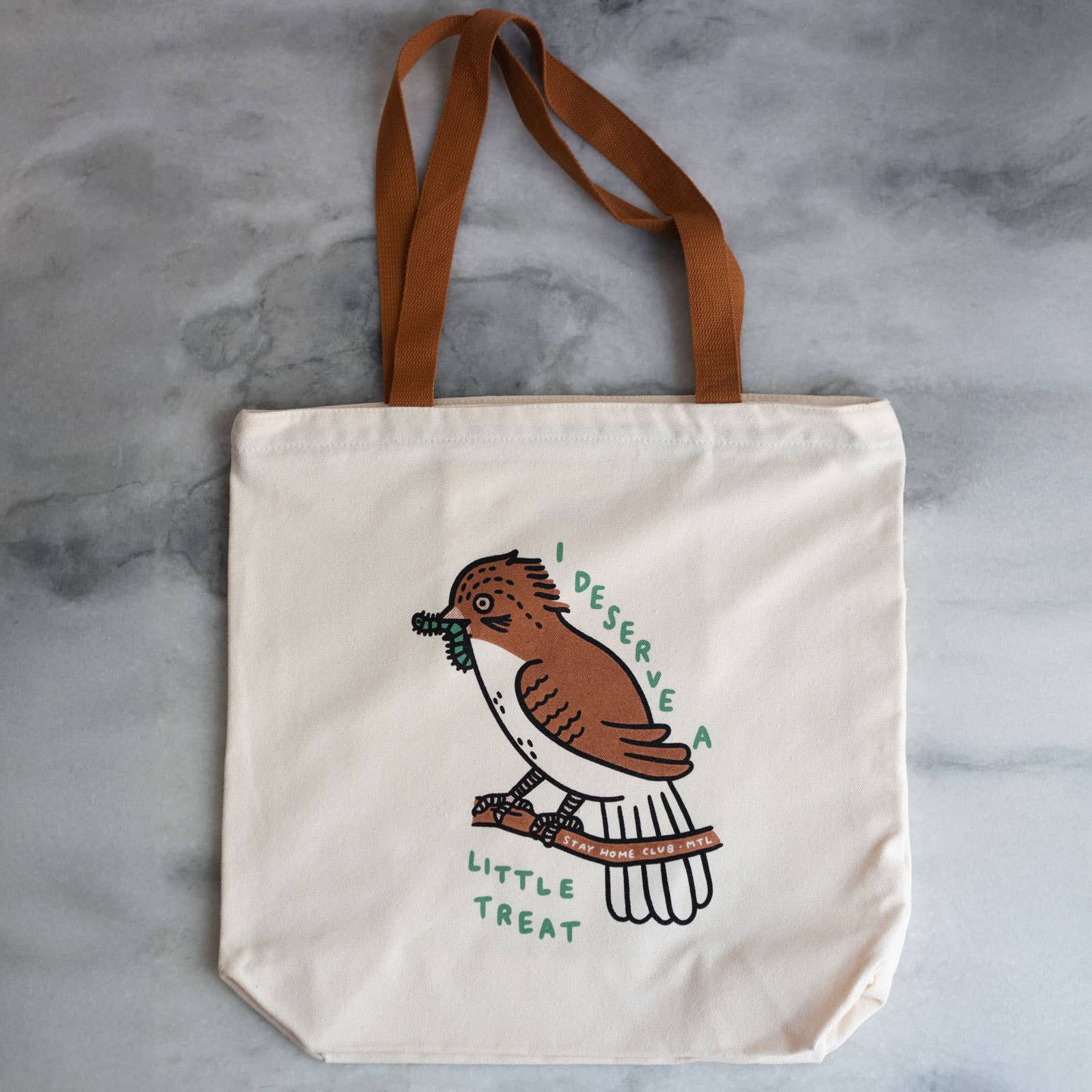 Tote bag with a bird illustration and text on a gray surface