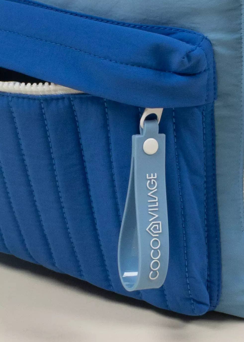 Blue bag with a visible brand tag on a neutral background