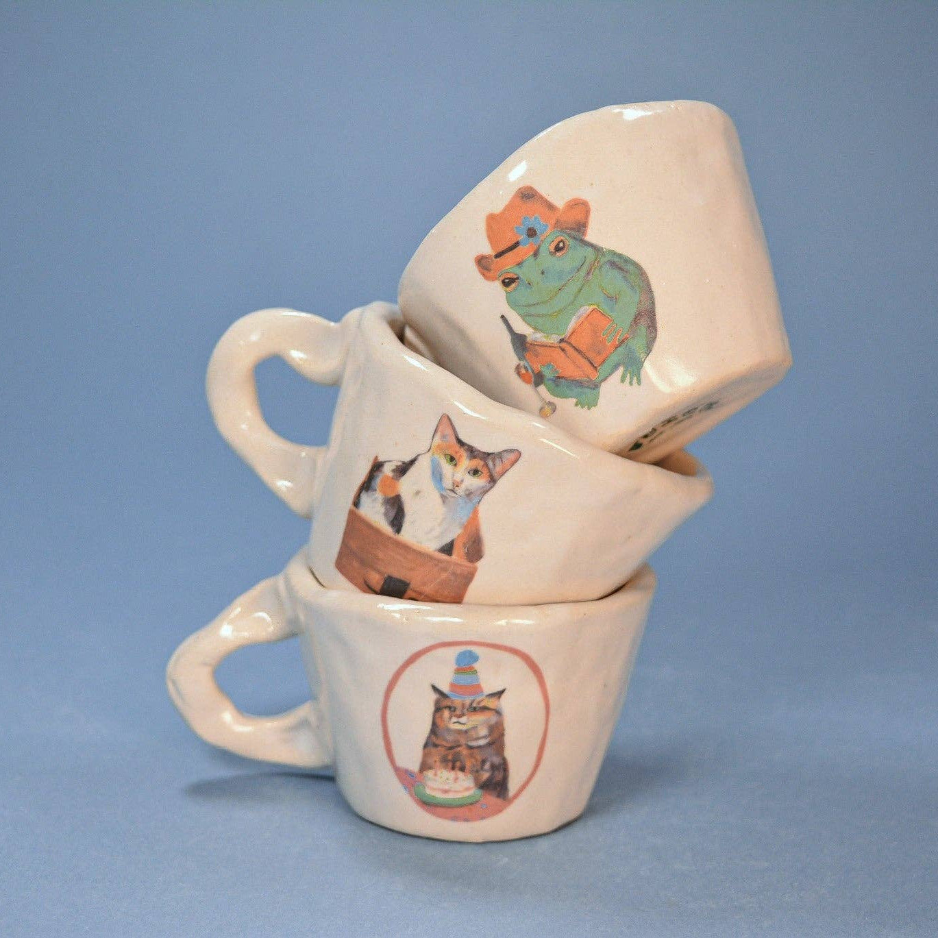 Stack of ceramic mugs with various animal illustrations on a blue background