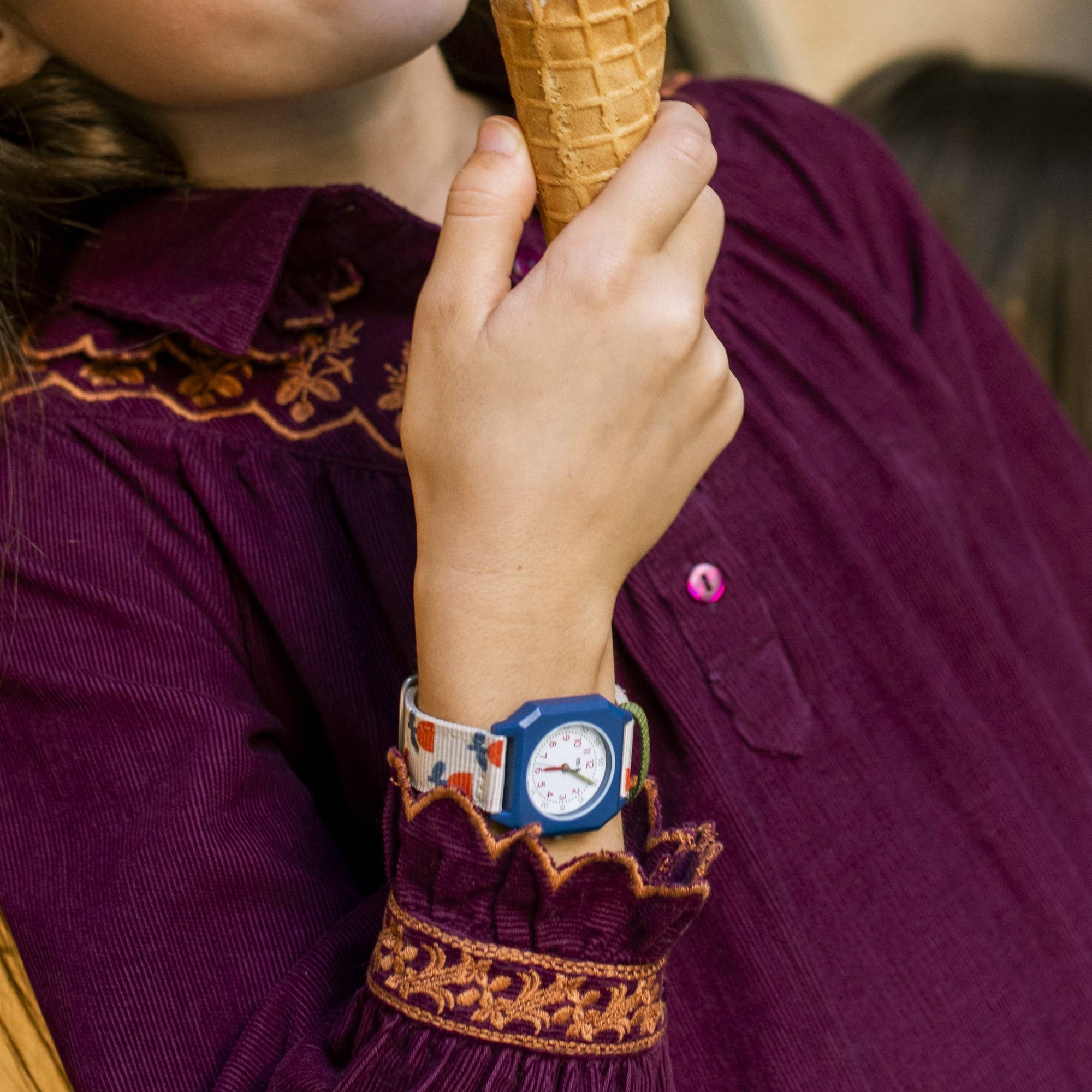 Person wearing a purple embroidered outfit holding an ice cream cone