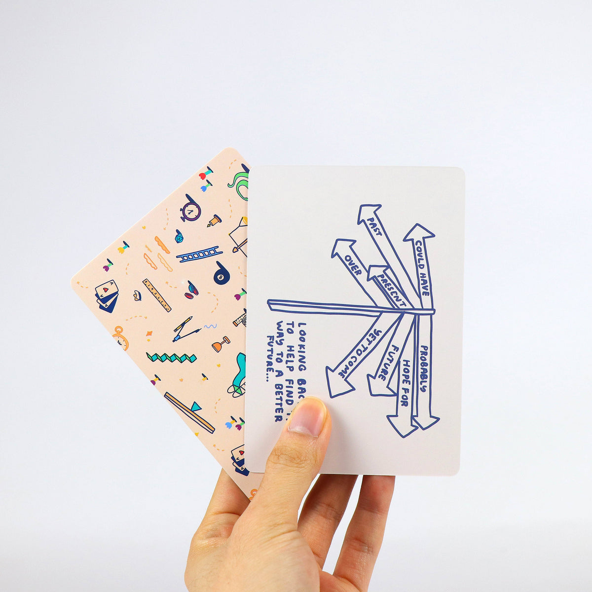 Hand holding two cards with different designs on a light gray background
