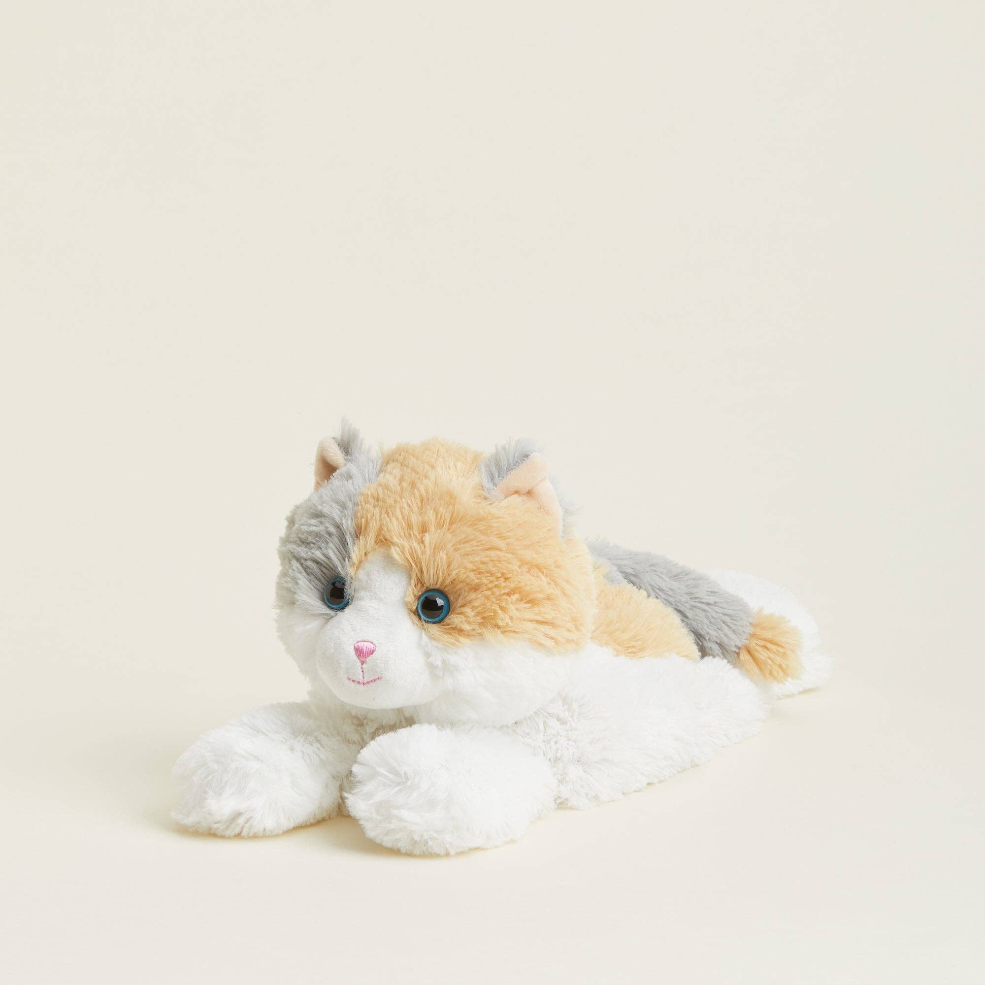Plush toy cat with a white, gray, and orange color pattern on a light beige background