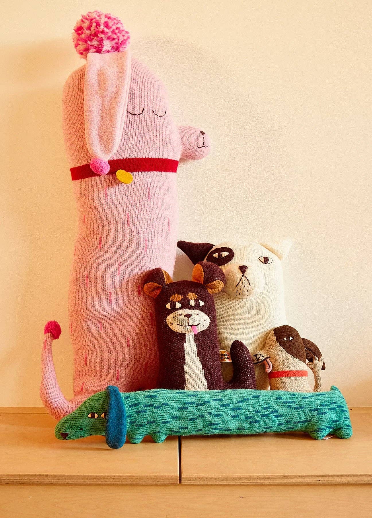 Collection of colorful knitted animals on a wooden surface with a light background