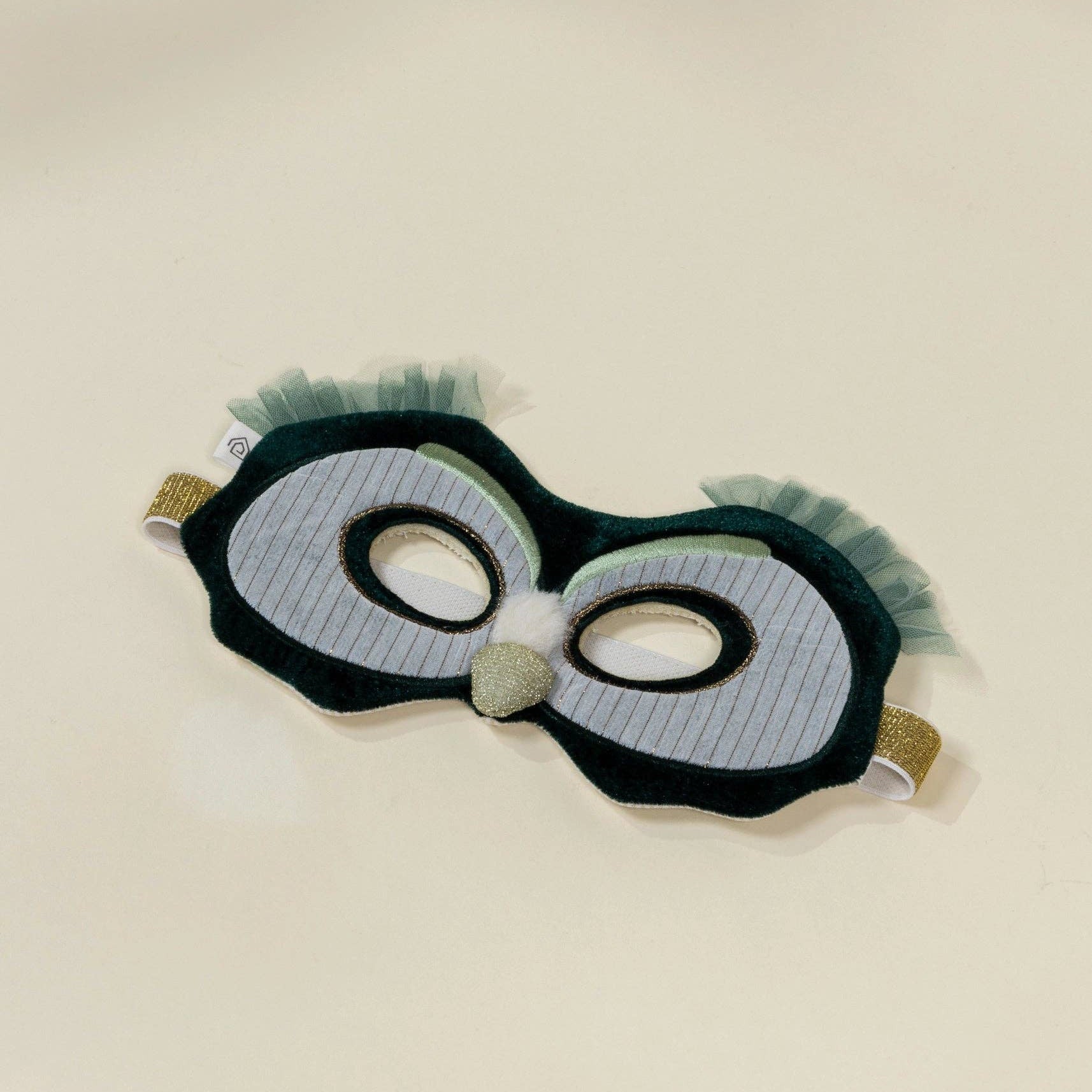 owl mask and green fringes on a beige background
