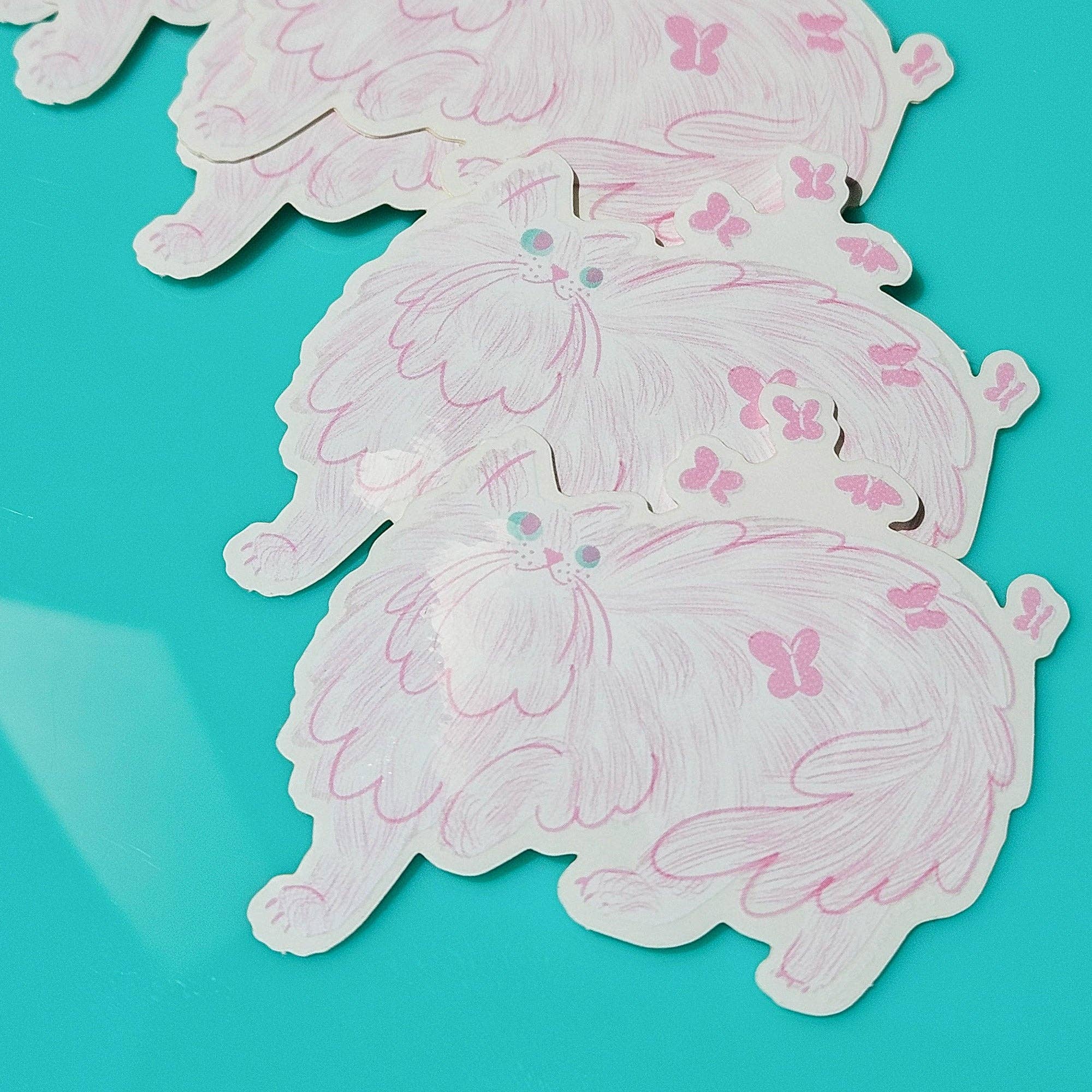 White stickers of cats with pink butterflies on a teal background