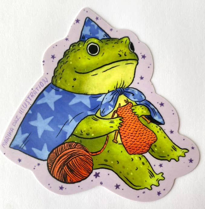 Illustrated frog character holding yarn and a crochet hook on a white background
