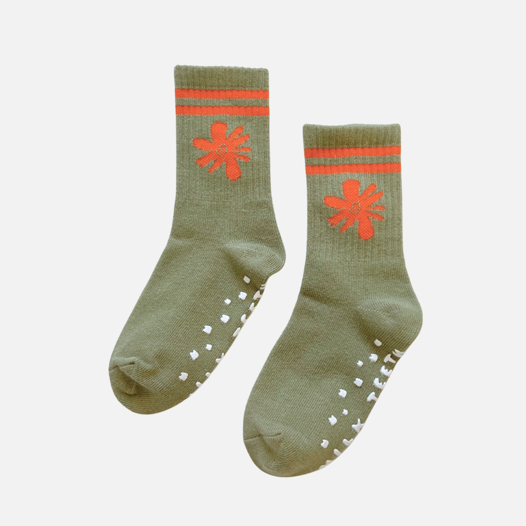 Pair of green socks with orange flower designs and sole patterns on a white background