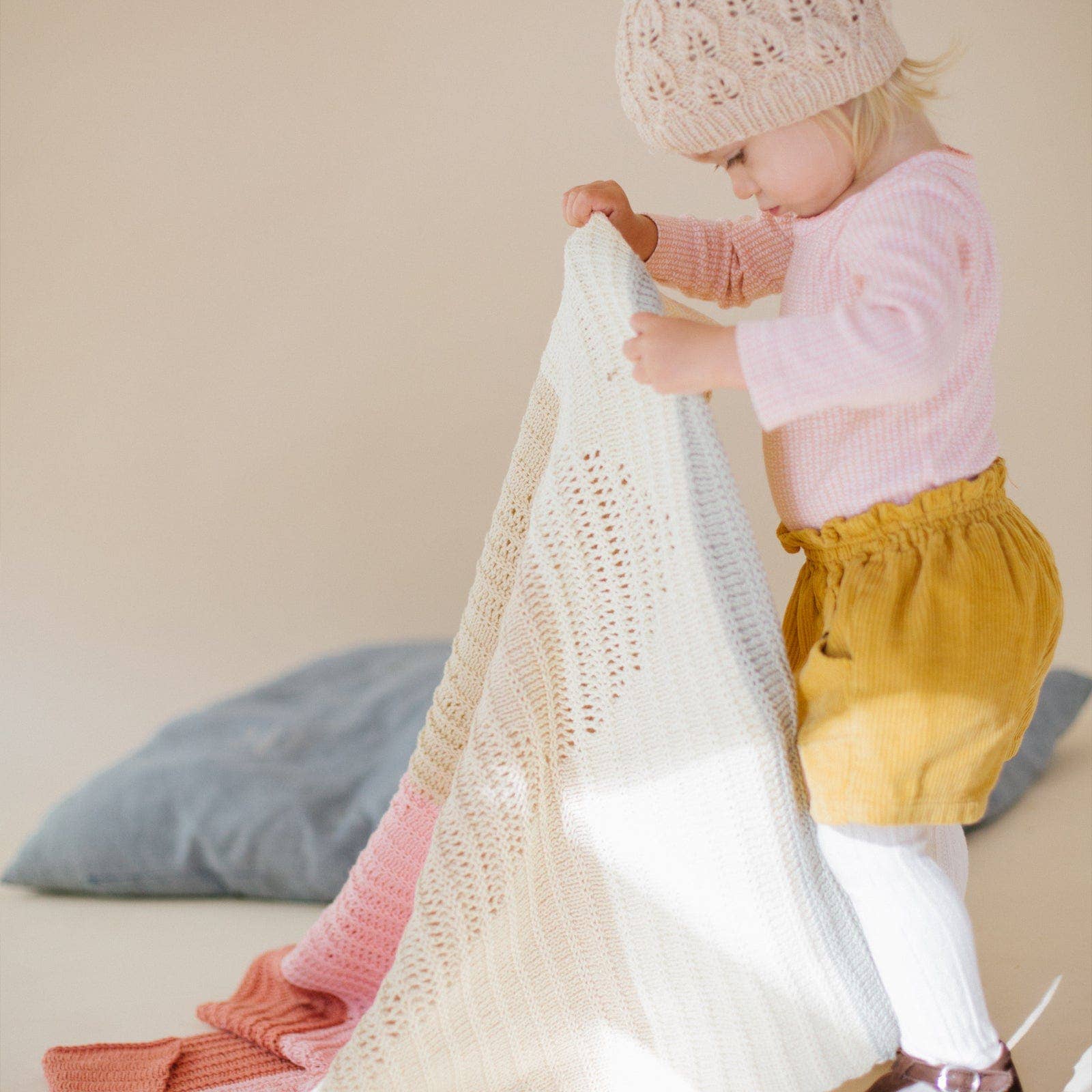 Child playing with a blanket on a soft surface