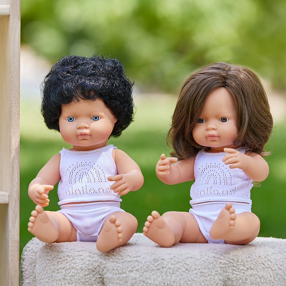 Two dolls with different hair colors sitting on a surface outdoors.