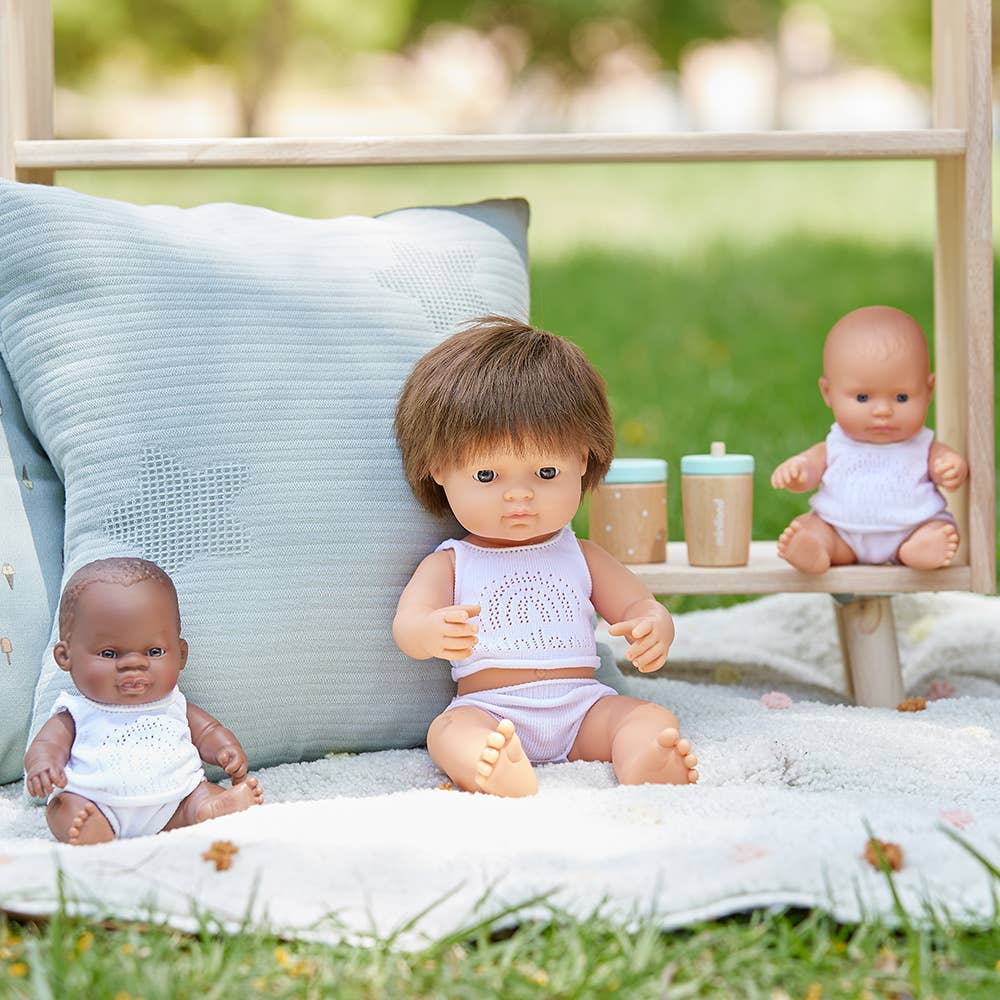 Three dolls on a blanket outdoors with a blurred natural background