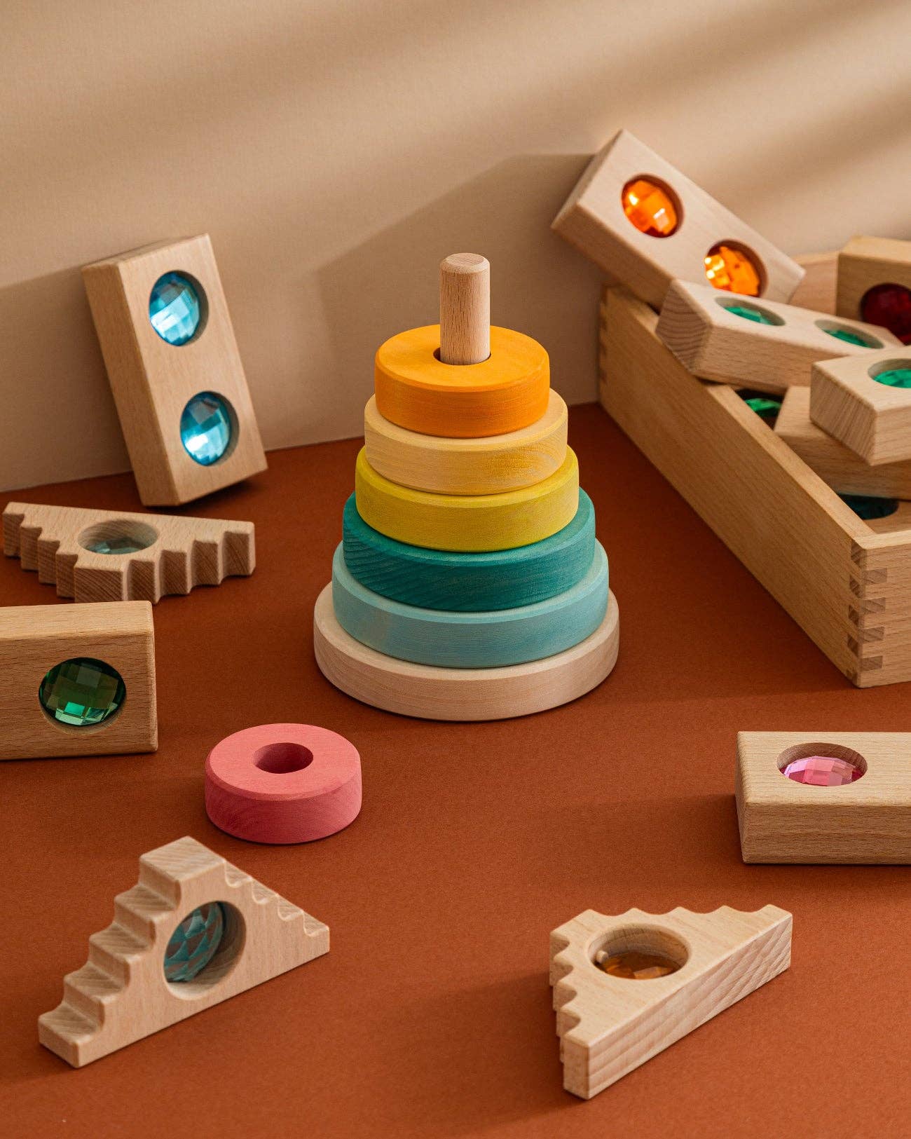 Colorful wooden stacking toy with various geometric shapes on a brown surface.