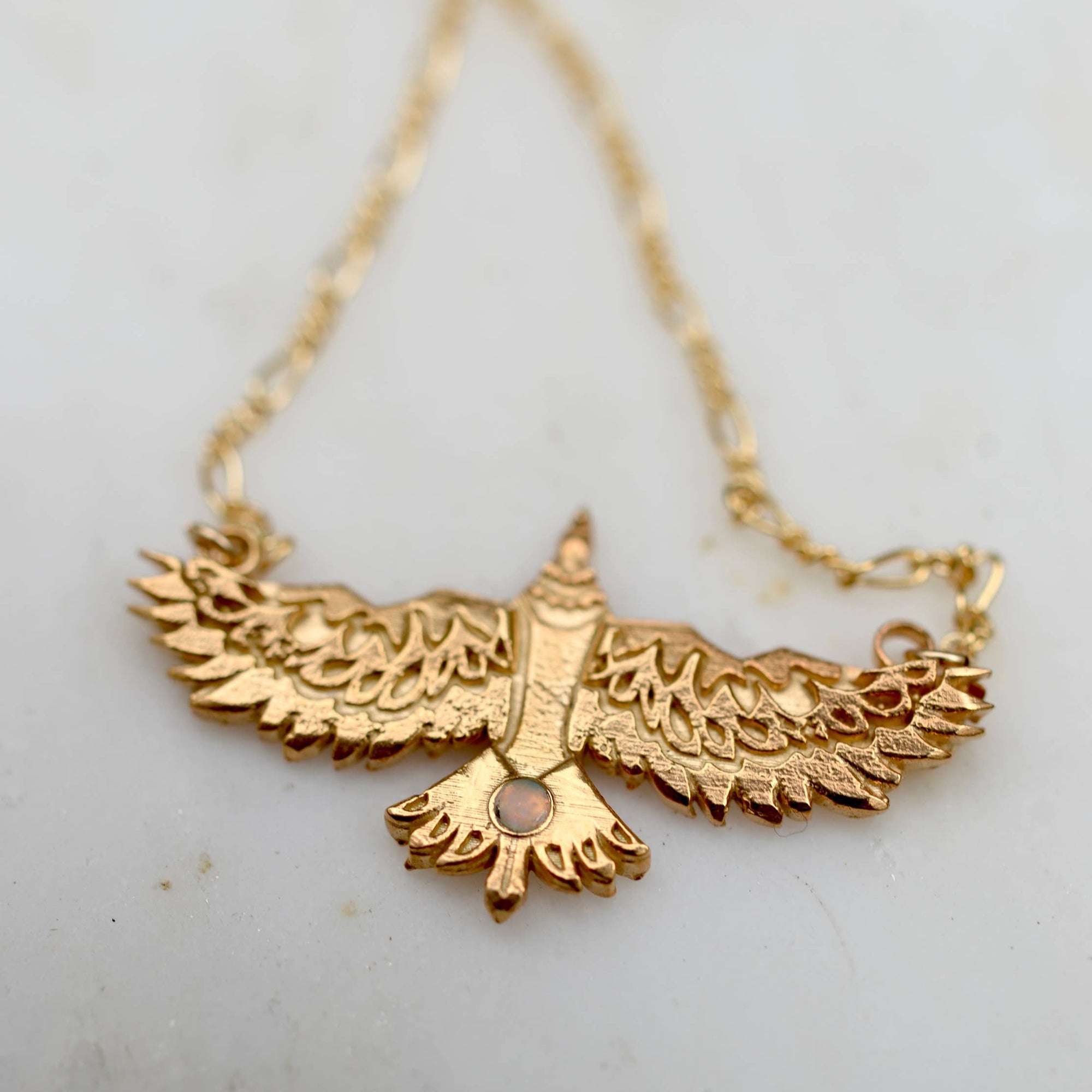 Gold bird-shaped necklace on a light background